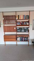 Full view of assembled teak wall unit with shelves, drawers, cabinet, magazine rack and glass case