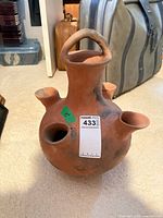Front view of spherical terracotta vase showing four side spouts, central neck and handle