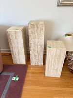 Three travertine pedestals of varying heights positioned side by side