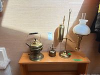 All three brass items on wooden shelf