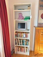 Full front view of white bookcase showing shelves and contents for scale