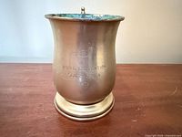 Front view of brass tankard showing engraving and patina