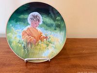 Front view of the plate showing child-in-meadow artwork and gold rim