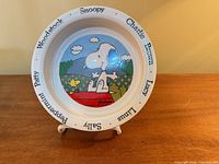Front view of Johnson Bros Snoopy ceramic plate on stand