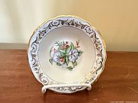 Front view of porcelain bowl on stand showing floral motif and gold gilt rim