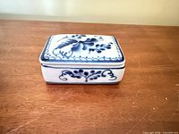 Closed trinket box showing top floral design and side motif