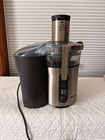 Front view of Breville stainless steel juicer showing control dial, pulp container, chute, and power cord