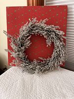 Front view of snow-covered artificial wreath against red background