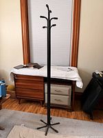 Full view of black metal coat rack showing hooks and base