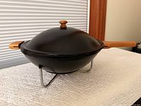 Side view of electric wok on stand showing lid, wooden handles and knob