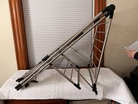 Side view of folding metal laundry drying rack set in triangular position