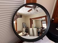 Round black-framed wall mirror reflecting room interior