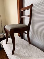 Side view of walnut-finish wooden chair on quilted surface