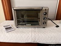 Front view of Black & Decker toaster oven and manual on table