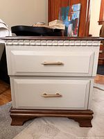 Front view of refinished side table showing two drawers, champagne bronze handles, walnut-stained top and feet