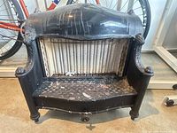 Front view of antique cast iron gas fireplace insert showing overall structure, decorative top, grate and ceramic radiator interior