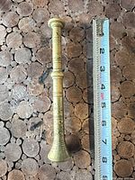 Brass pestle full view beside measuring tape