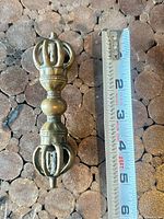 Full view of brass vajra with tape measure showing length