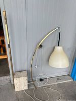 Full view of lamp showing travertine base, brass arm, dome shade and cord