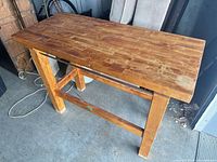 Full view of wood kitchen island table showing top, legs, and stretcher