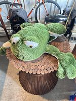 Full view of large green frog plush on table