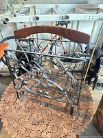 Front view of black wrought iron magazine rack with wooden handle