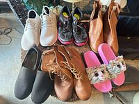 First image showing six footwear pairs on round table