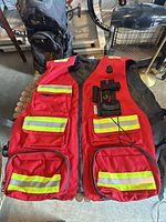 Front view of red safety vest displaying pockets, reflective strips and size tag
