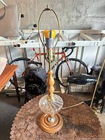 Full view of lamp showing wood stem, glass section, brass fittings, harp and bulb