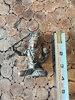 Full view of bronze Manjushri figurine with ruler for scale