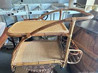 Full view of rattan bar cart showing two shelves and bottle holder