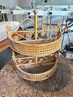 Front view of semi-circular rattan two-tier shelf showing scroll details and wooden shelves