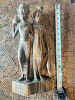 Full view of wood carved twin female figure statue with tape measure for scale