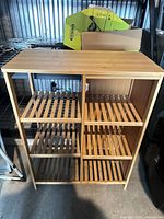 Front view of light wood shelving unit showing solid top and slatted shelves