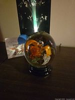 Glass paperweight with multicolour interior and pedestal, fiber optic lamp in background