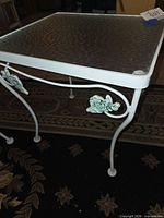 Full view of table showing glass top and one side with leaf detail