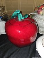 Front view of red ceramic apple cookie jar with green stem lid
