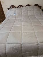 Full view of silver quilted comforter on bed