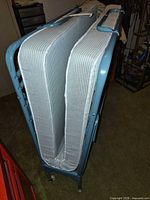 folded light blue metal rollaway bed with striped mattress