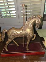 Side view of brass carousel horse figurine on wood base showing overall appearance