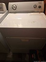 Full front view of white Whirlpool gas dryer next to washer