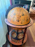 Full view of closed globe bar showing map motif and stand