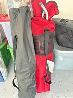 Red and black carry bags standing upright containing the two folding chairs