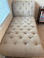 Full view of chaise lounge showing upholstery, tufting, and overall shape