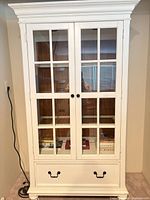 Front view of white Havertys display cabinet with double glass doors and lower drawer