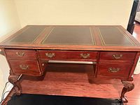 Front view of mahogany writing desk showing drawers, brass handles, cabriole legs