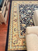 Corner of rug beside TV stand and sofa showing border and main field design