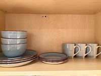 Stacked bowls, dinner plates, salad plates, mugs on shelf