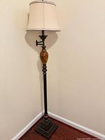 Full view of floor lamp standing in corner with shade and base visible