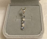 Front view of pendant in display box showing alternating alexandrite and diamond stones